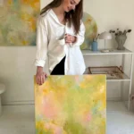 žena se opírá o žluto-zelený abstraktní obraz