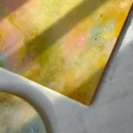 detail žluto-zeleného obrazu a kousek kulatého obrazu na zemi