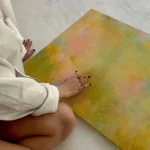 detail ruky, která se dotýká abstraktního zeleného obrazu