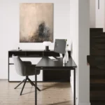 opřený šedo-černý abstraktní obraz v místnosti s pracovním stolem