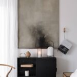 šedo-černý abstraktní obraz nad černou komodou