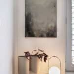 šedý abstraktní obraz nad lampičkou a dekorací