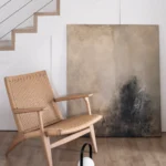 opřený šedo-černý abstraktní obraz a před ním křeslo