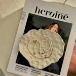 časopis s ženou a na tom béžová miska ve které jsou šperky z perel
